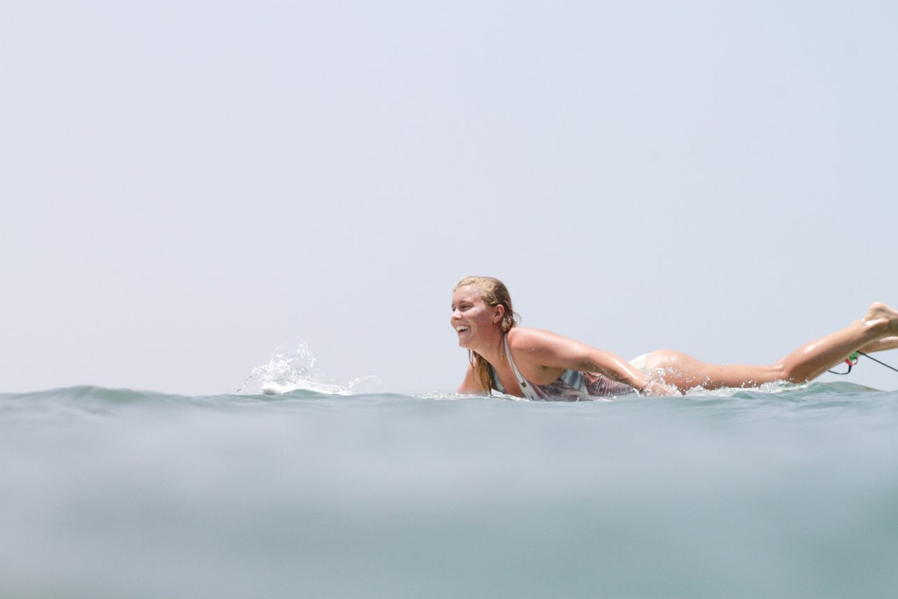 surfer girl paddling ocean happy